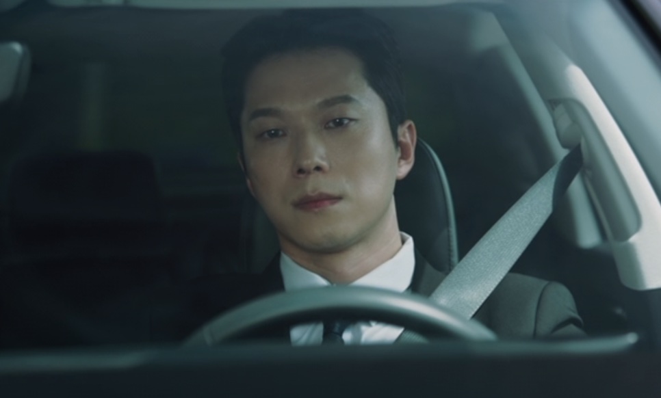 Han Jong-hyun ao volante de um carro, visto pelo para-brisa, em Flex X Cop 2