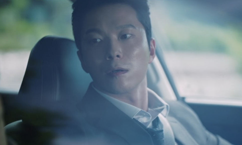 Han Jong-hyun dentro do carro, virando o rosto para trás com ar de surpresa, em Flex X Cop 2