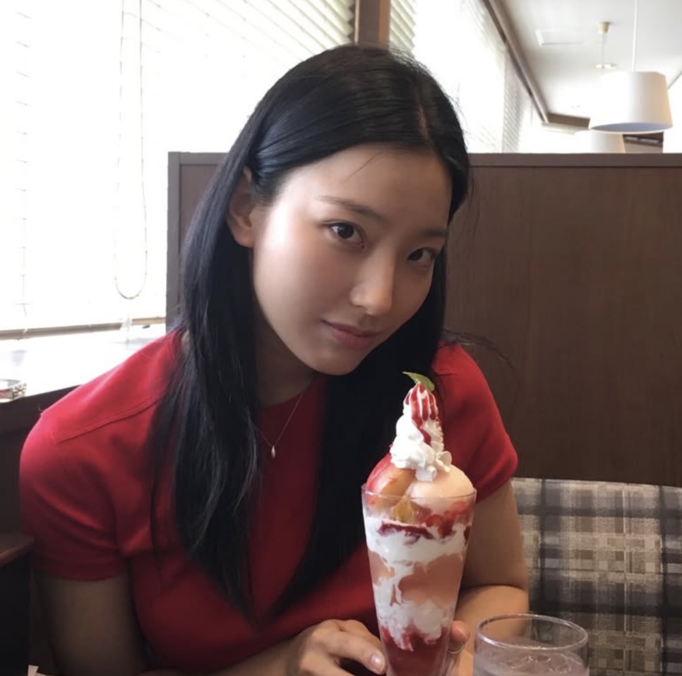 Lee Sae-rom de blusa vermelha, sentada num café com uma taça de sobremesa de morango