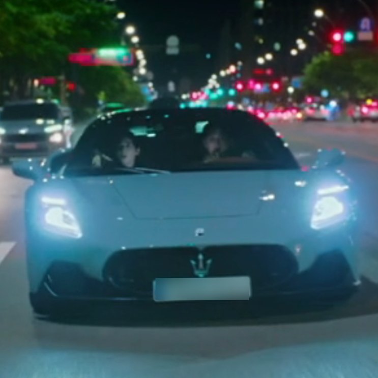 Maserati esportiva de teto aberto rodando à noite por uma avenida iluminada