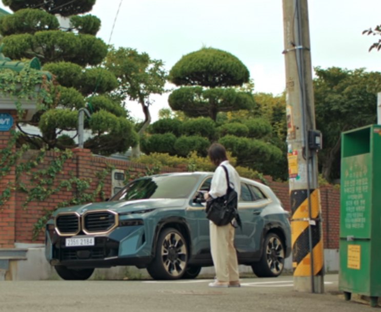BMW XM parada na calçada de uma rua, com uma pessoa de costas ao lado
