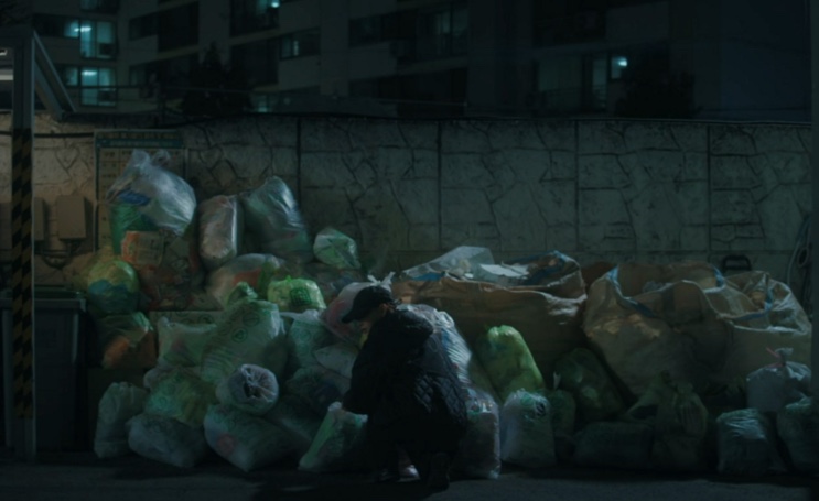 Pilha de sacos de lixo encostada no muro de um prédio, à noite