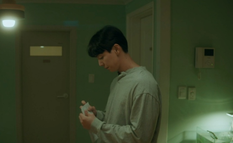 Woo-jae de costas, segurando um saquinho com um peixe dentro