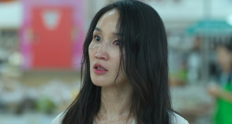 Park Bo-kyung de cabelo comprido, falando em frente a um mercado