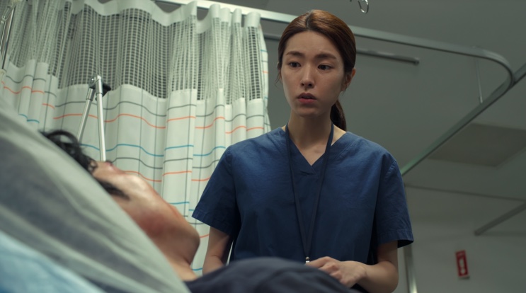 A enfermeira Yoon atrás da cortina do hospital, em Cães de Caça