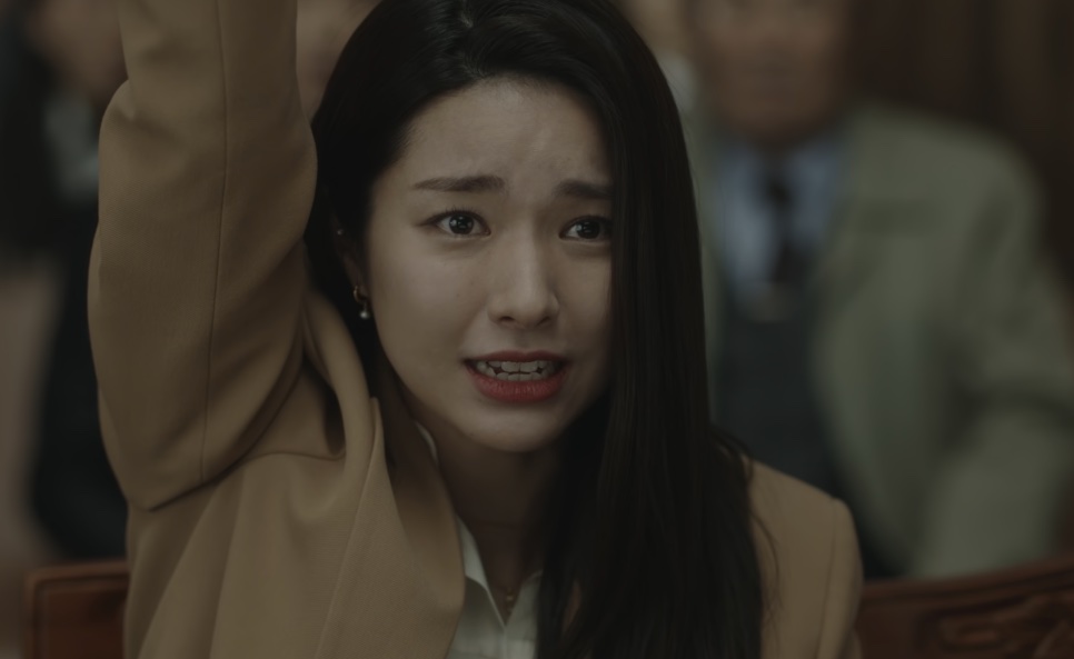 Kim Hwa-young chorando no tribunal com o braço erguido, pedindo a palavra