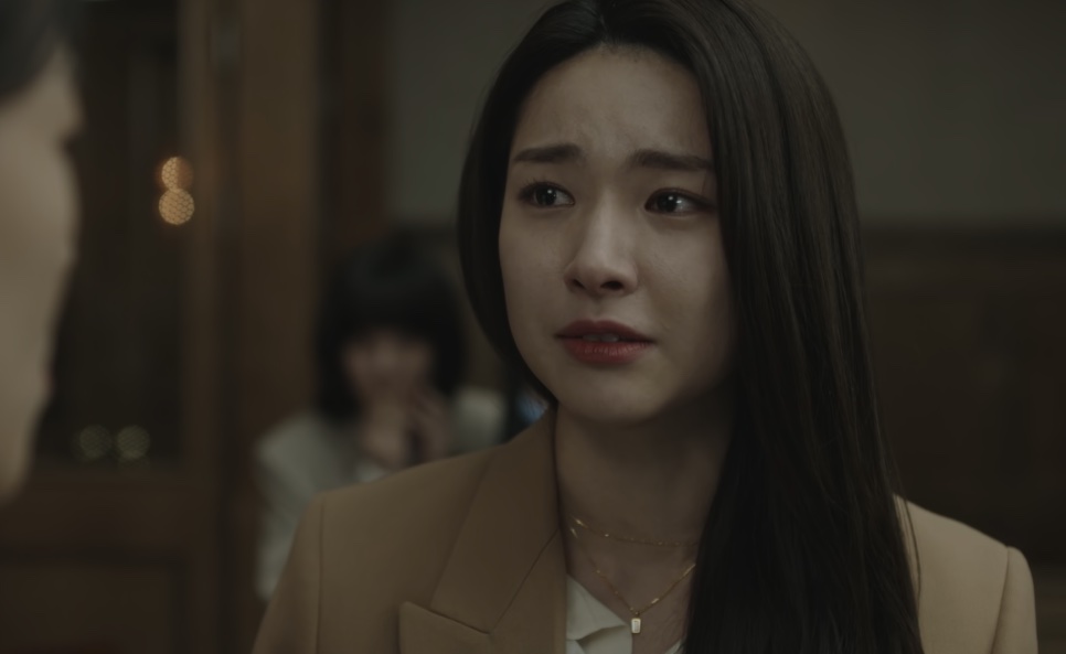 Kim Hwa-young chorando enquanto fala, de casaco bege, no tribunal