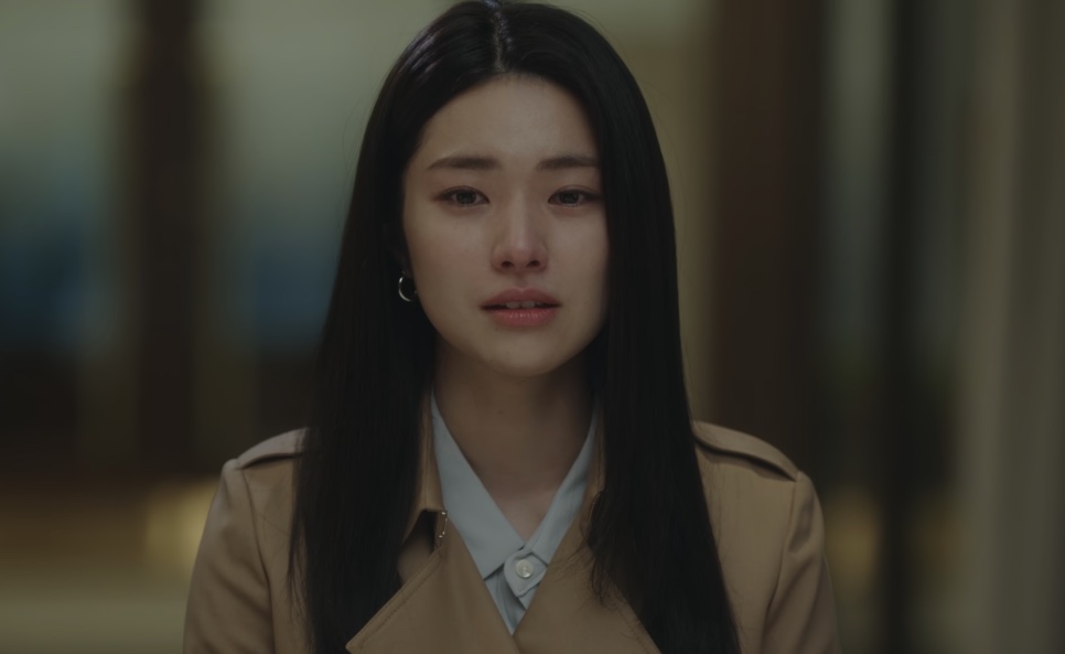 Close de Kim Hwa-young chorando, de casaco bege, com o cabelo solto