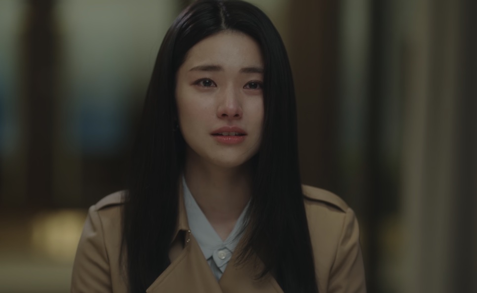 Kim Hwa-young de casaco bege chorando no tribunal, de perfil