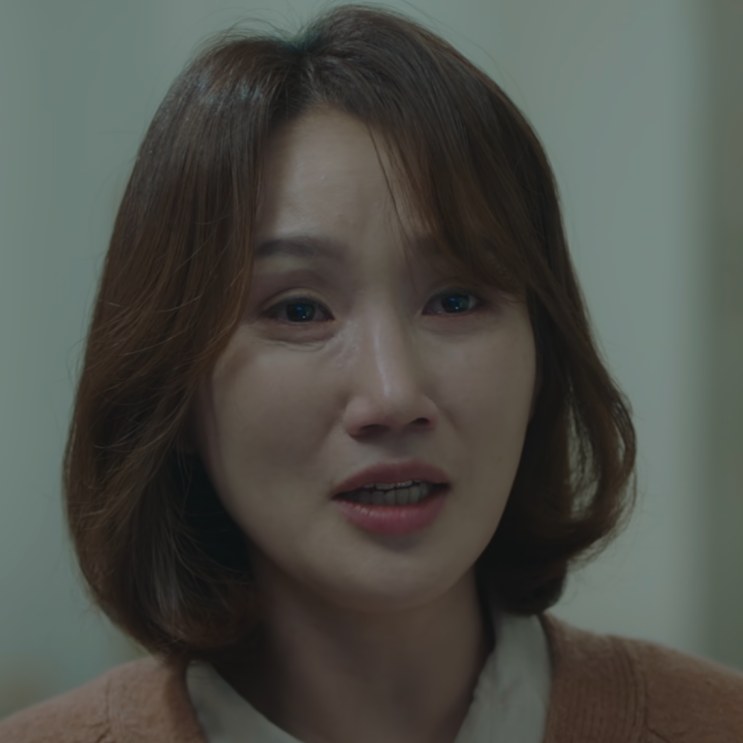 Close no rosto da esposa do paciente, interpretada por Park Bo-kyung, falando com alguém