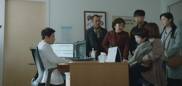 Vista geral do consultório, com o médico de um lado e a família do outro