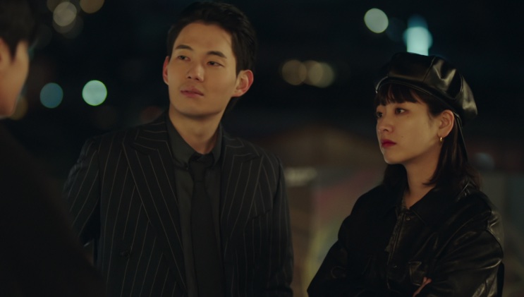 Duas pessoas conversando com Ma Hyun-yi em uma rua à noite