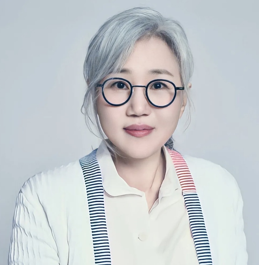 Retrato da roteirista Kim Eun-sook, de cabelo grisalho e óculos redondos