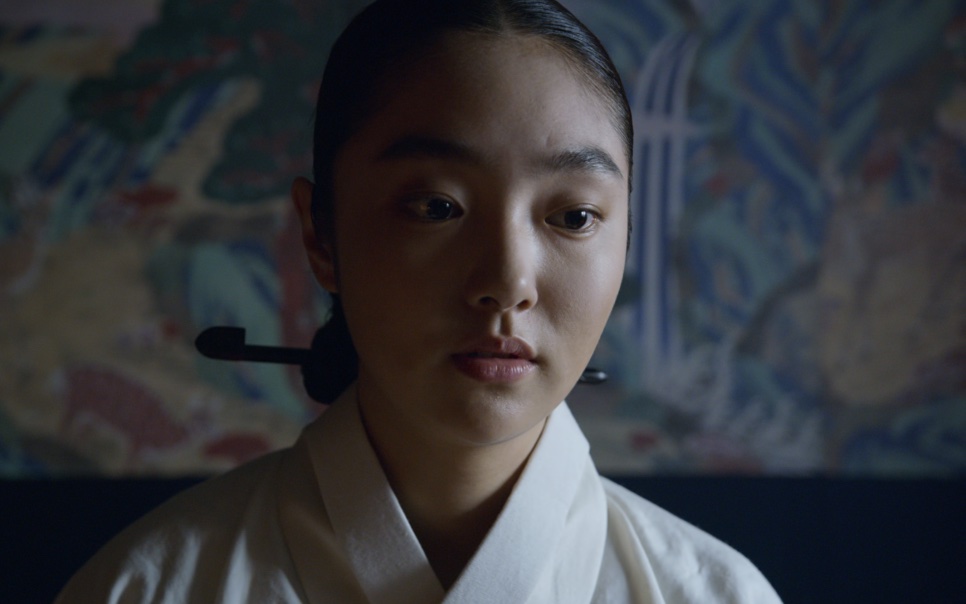 A rainha de Kingdom de hanbok branco, com o cabelo preso, olhando para baixo