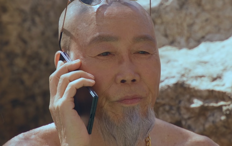 Jo Pyeong-gyeon, um homem careca de barba branca, falando ao celular