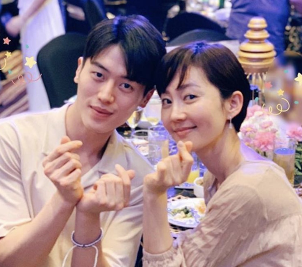 Lee Joo-ahn e uma atriz fazendo coraçãozinho com os dedos numa mesa de festa