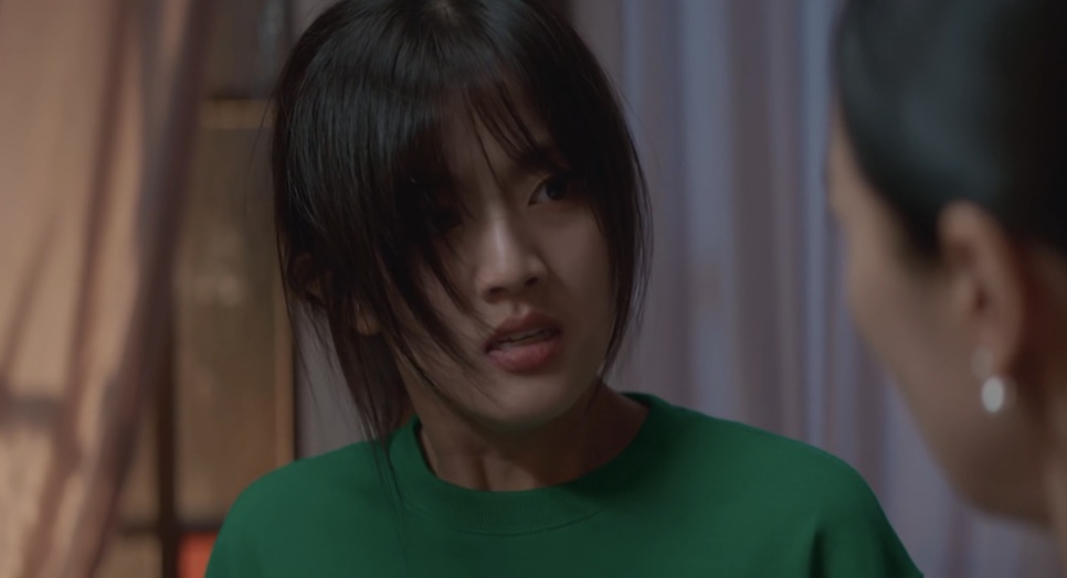 Yoon Cheong-a de camiseta verde, com o cabelo no rosto, encarando uma mulher com medo