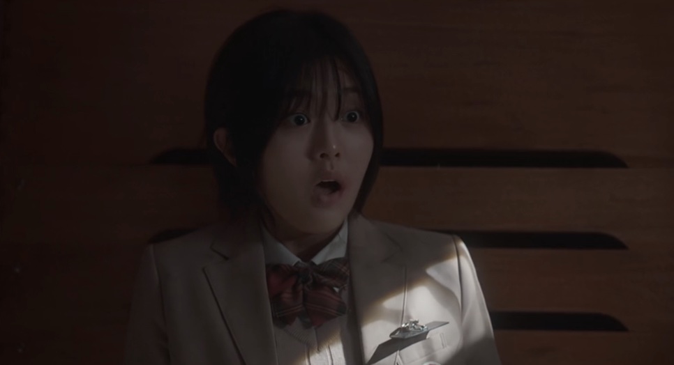 Yoon Cheong-a de uniforme, com cara de espanto, num depósito escuro