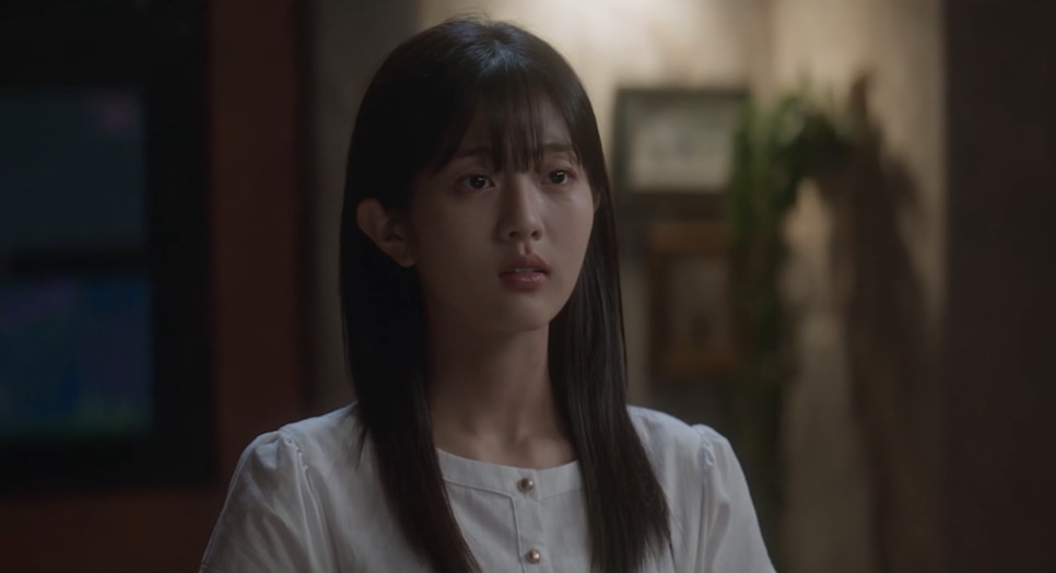 Yoon Cheong-a de blusa branca, com o cabelo solto, num quarto à noite