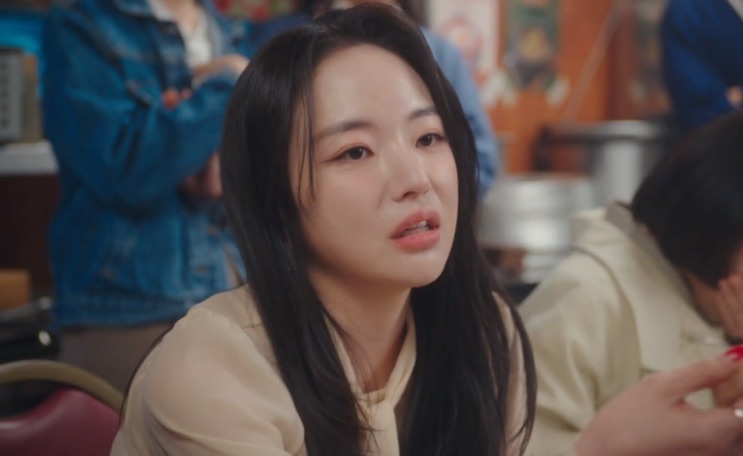 Seo Hye-su de perfil, falando alguma coisa, num restaurante cheio