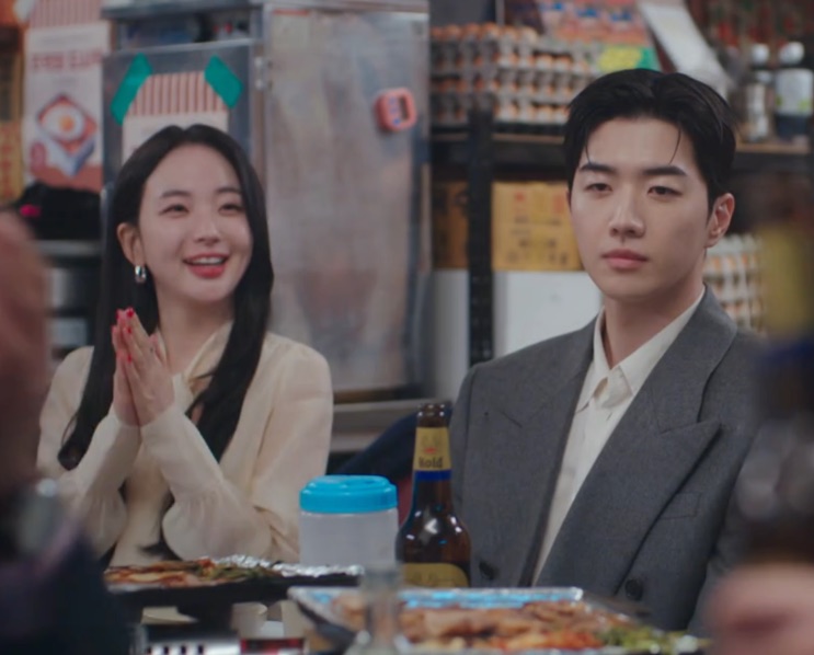 Seo Hye-su batendo palmas ao lado de um colega, numa barraquinha de comida