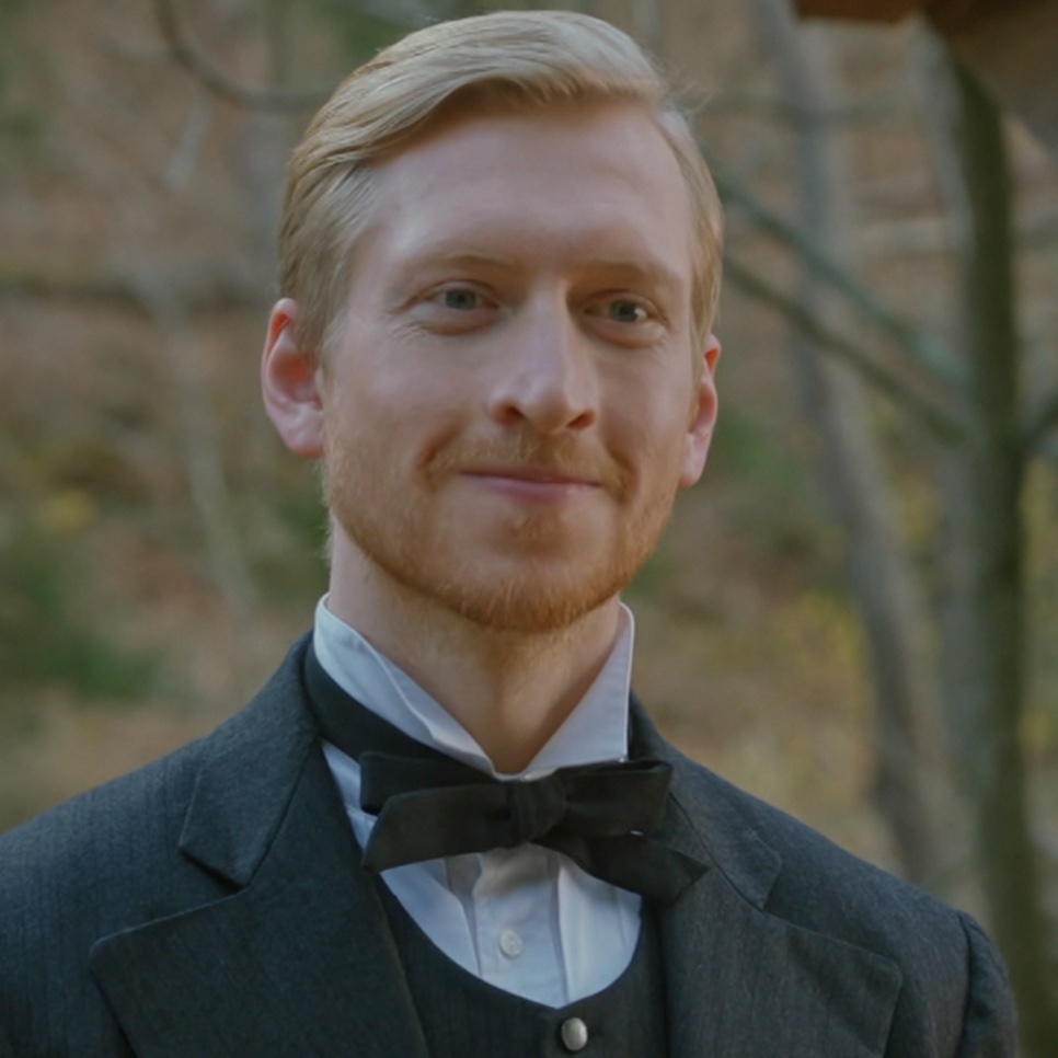 Jason Nelson de terno escuro e gravata-borboleta, sorrindo, no papel de Joseph Stenson em Mr. Sunshine