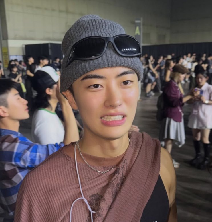 Lee Won-jung de gorro e óculos escuros na testa, no meio de um evento
