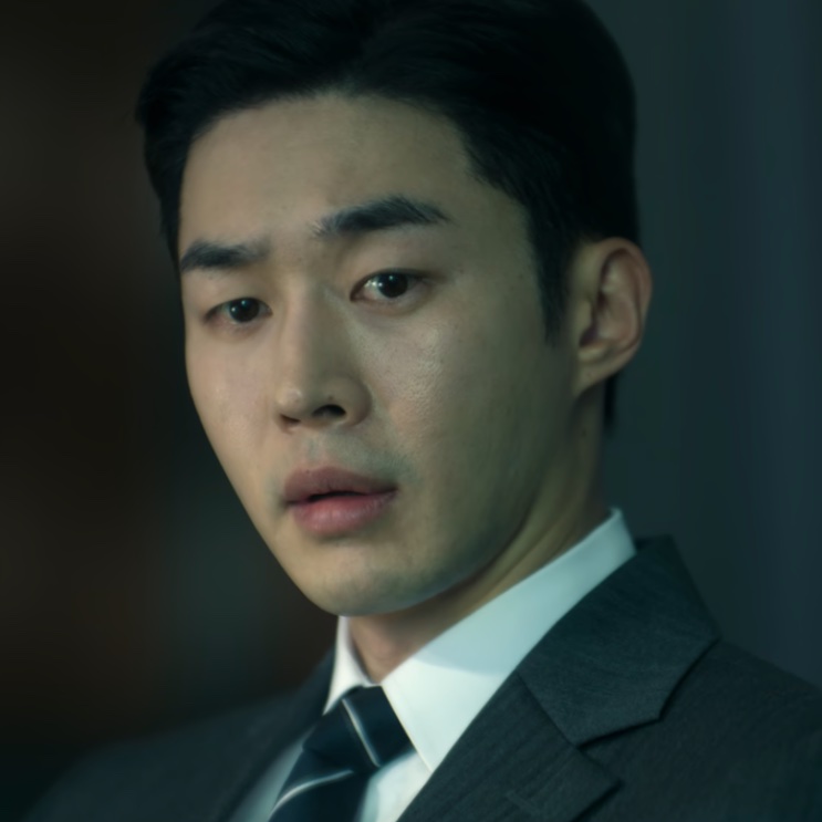 Son Soo-hyun de terno e gravata, olhando para o lado com expressão tensa