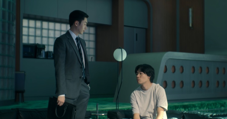 Son Soo-hyun em pé conversando com o Moon-jae, que está sentado no quarto