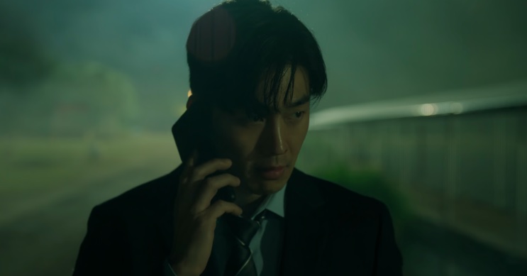 Son Soo-hyun falando ao telefone à noite, com o rosto na sombra