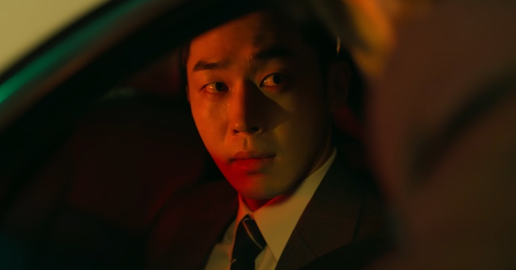 Son Soo-hyun dentro do carro olhando para o lado, com luz vermelha no rosto
