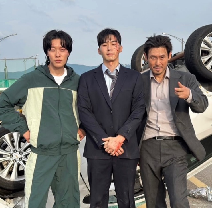 Moo Jin-sung ao lado de outros dois atores do elenco, em foto de bastidores