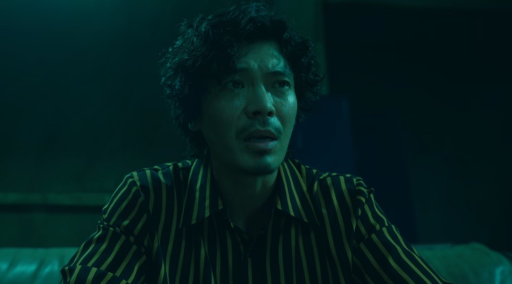 Close de Seung-gyu falando em um ambiente de luz esverdeada