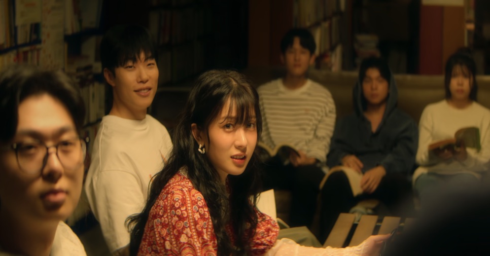 So Min-yeong de blusa estampada vermelha, falando no meio do grupo do clube de literatura