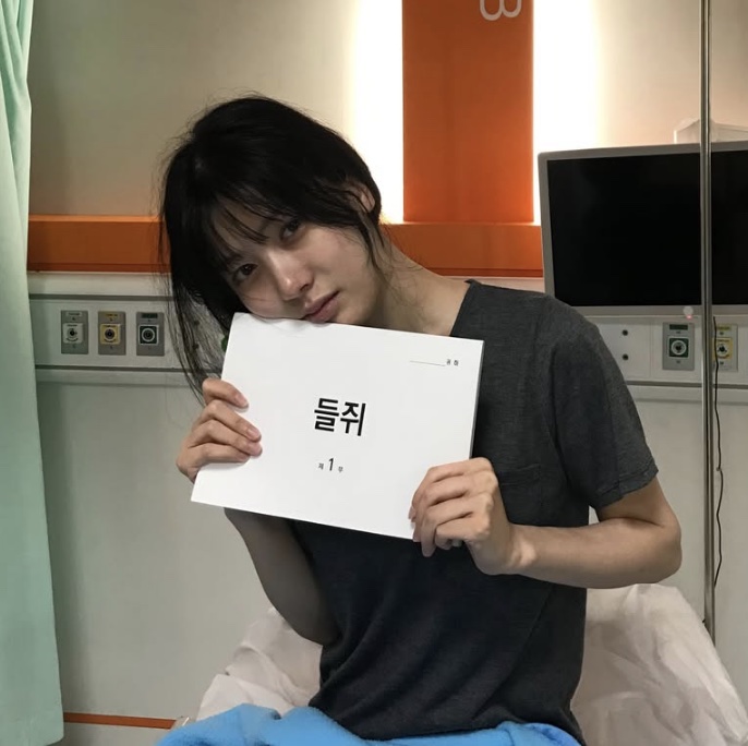 Song Su-yi segurando o roteiro de O Rato, sentada em uma sala de hospital