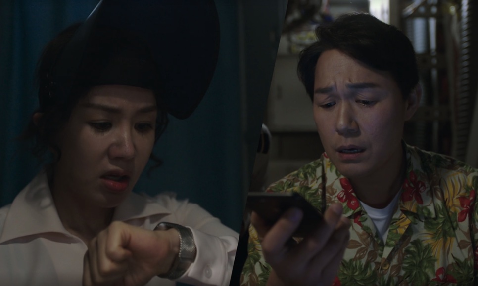 Tela dividida: a Mi-young olhando o relógio e o marido, Seok-hwan, de camisa florida, falando ao celular