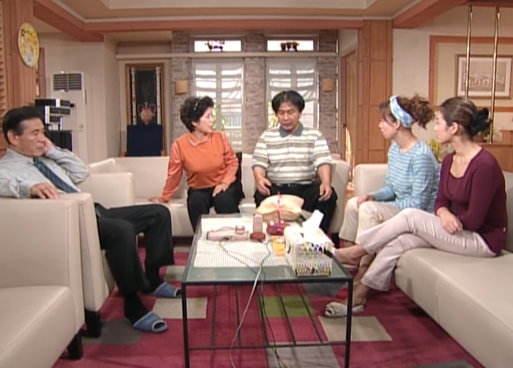 Família reunida no sofá da sala, cena antiga de sitcom dos anos 1990