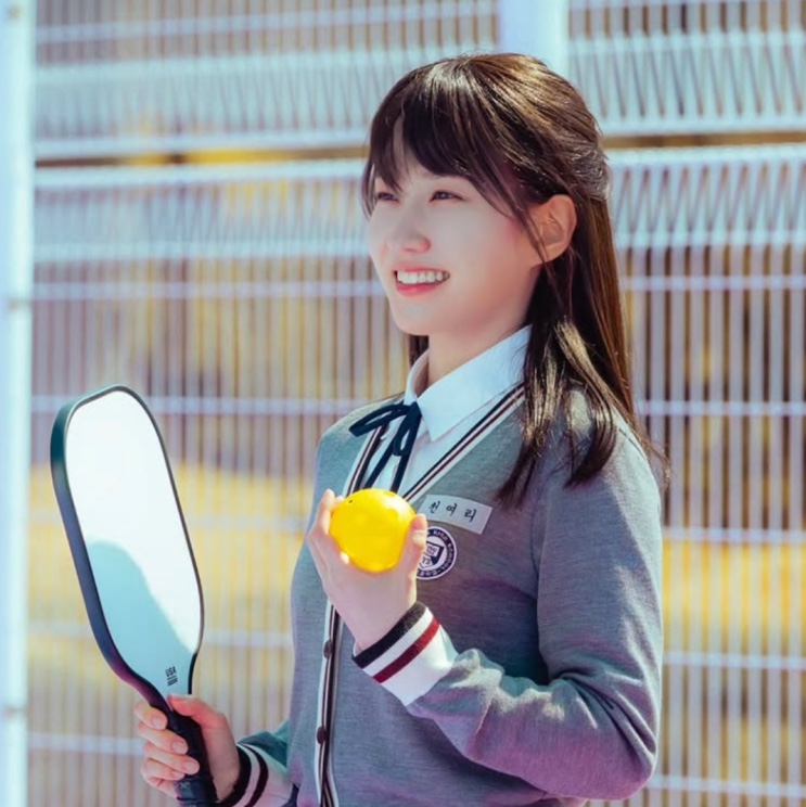Park Eun-bin de uniforme escolar, segurando uma raquete e um limão