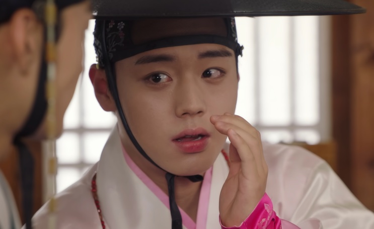 Park Ji-hoon de hanbok rosa e chapéu tradicional, em cena de Os Casamenteiros de Joseon