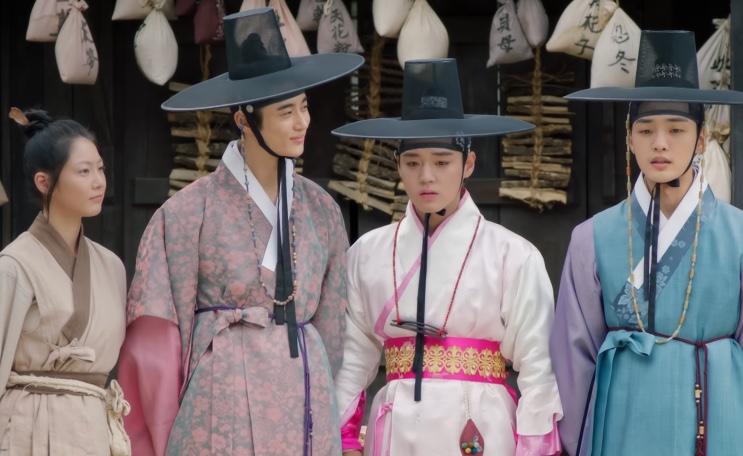Quatro personagens de Os Casamenteiros de Joseon, de hanbok, em uma rua de Joseon