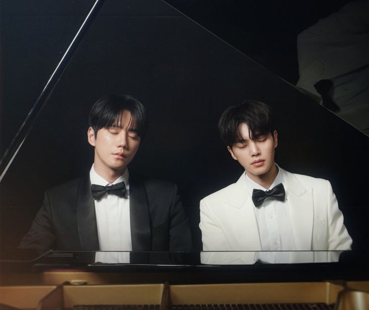 Dois rapazes de smoking sentados ao mesmo piano de cauda