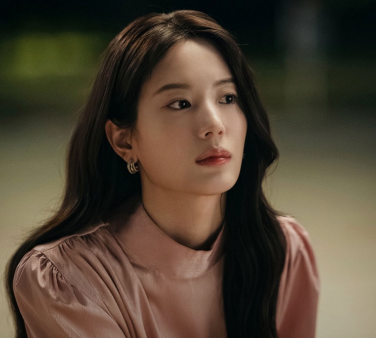 Jang Gyu-ri de blusa clara, olhando para longe