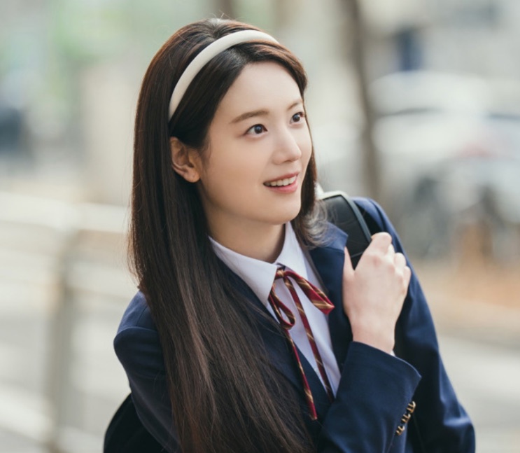 Jang Gyu-ri de uniforme escolar com a mochila no ombro, andando na rua