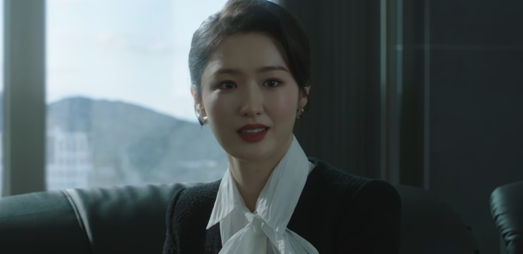 Jin Ye-jun de pé em uma sala de escritório, olhando para o lado