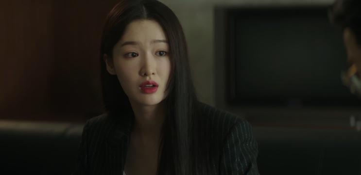 Jin Ye-jun de cabelo solto, falando em uma sala escura