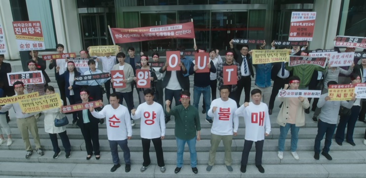 Manifestantes em frente a um prédio, erguendo faixas em um protesto