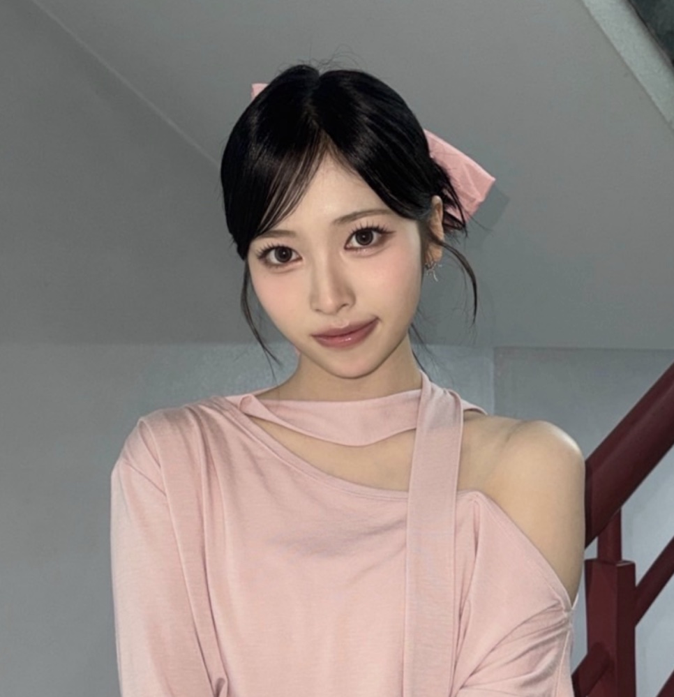 May, do Rescene, de blusa rosa e laço no cabelo, olhando para a câmera