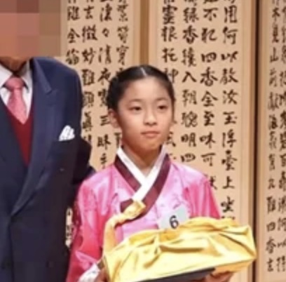 May criança, de hanbok rosa e com um número preso na roupa, numa competição de cerimônia do chá