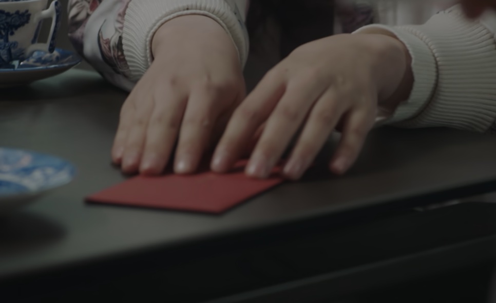 Mãos colocando um envelope vermelho sobre a mesa