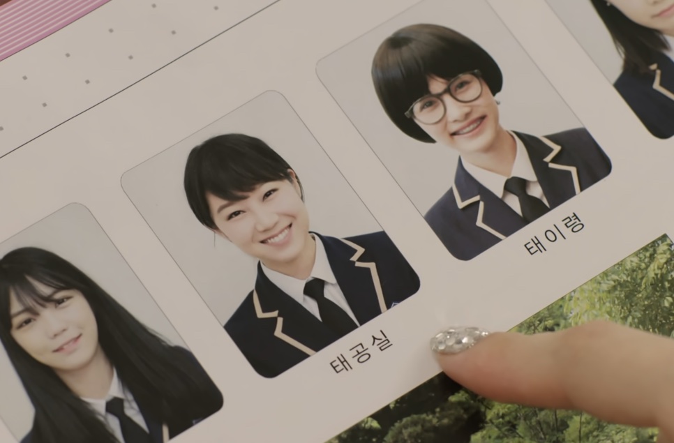 Página de anuário escolar com as fotos de colégio da Tae Gong-shil e da Tae Yi-ryung, de uniforme, lado a lado